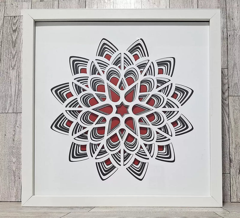 cut layers of black and white paper over a red background in a white frame